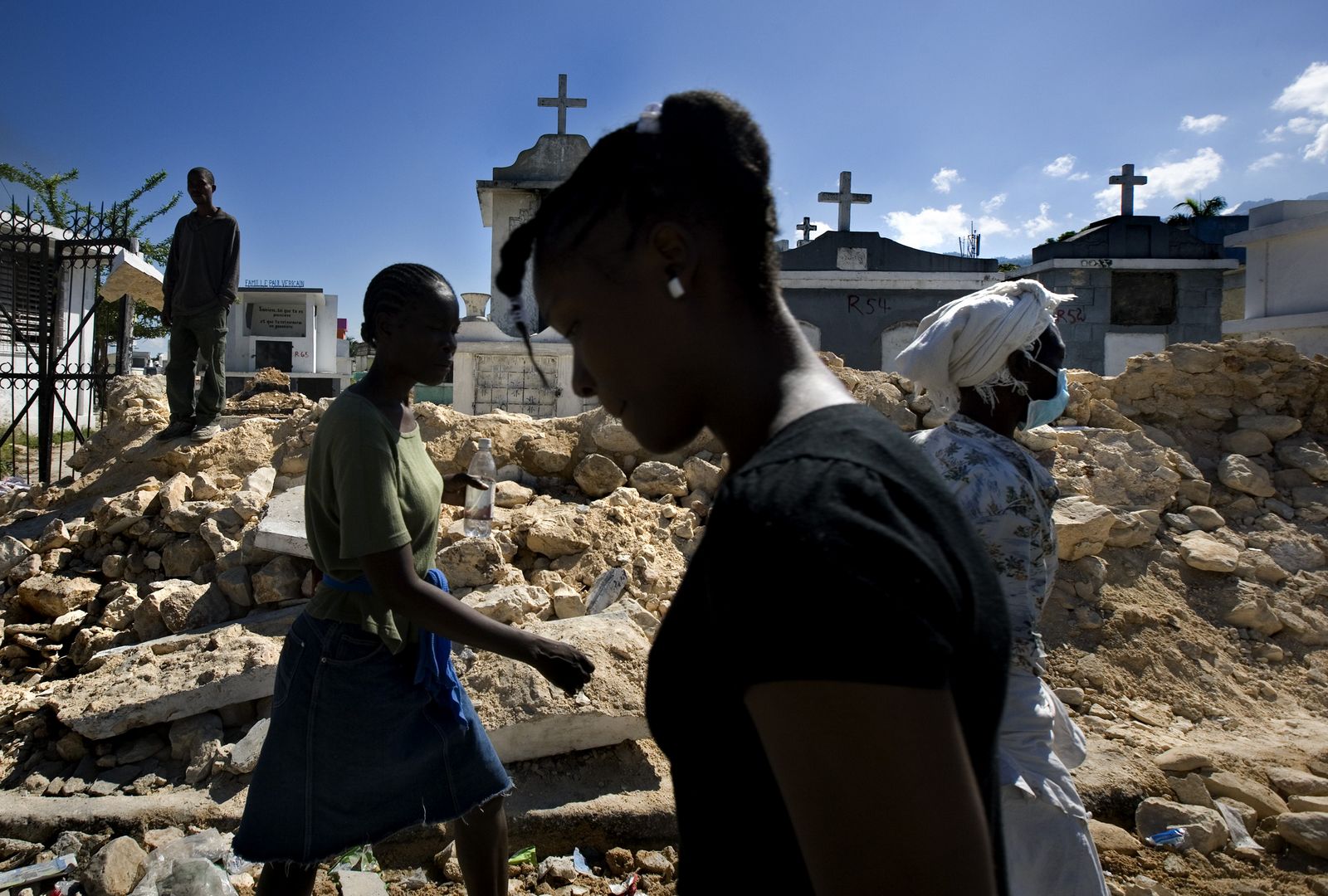 Port-au-Prince residents walk past a damaged cemetery.