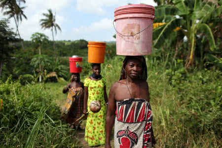 Women collect water from a waterhole in Tanzania. Image: Josh Estey/CARE.