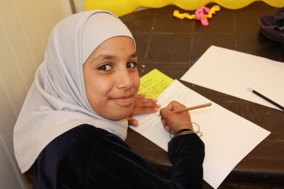 young girl in Syrian refugee camp participating in education program provided by CARE