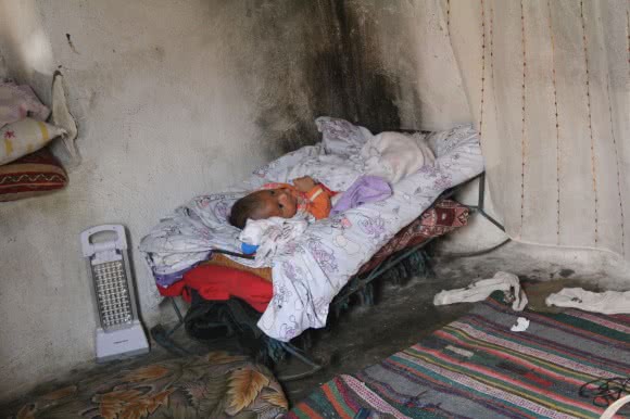 Baby Camar, aged just a month and a half, came to Turkey from Syria aged just days old. His family of eight share this room. ©Kathryn Richards/CARE