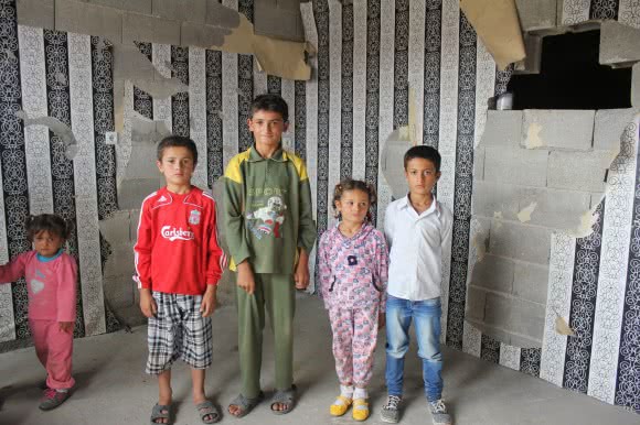 Children gather in a makeshift warehouse shelter in Nizip having fled from Kobane. The possessions of eight families lie on the floor, they fled with very little. ©Kathryn Richards/CARE