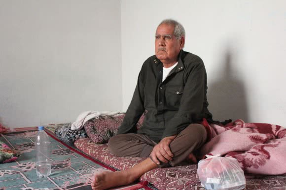 Seventy-year-old Ismail Yousef Hessi came from Kobane when the town came under bombardment. After spending a night on the border, he sits next to a bag of his much-needed medicine. He has just a few days of medicine left. ©Kathryn Richards/CARE