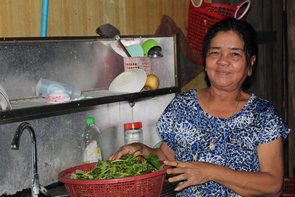 Lady standing proudly in kitchen, washing fresh produce