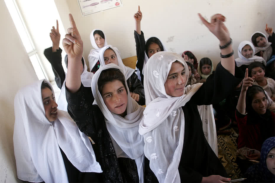 Students raise their hands at a school in a small village in the Shomali Plains just north of Kabul, Afghanistan. CARE funded the construction of a library at the school. ©Kate Holt/CARE