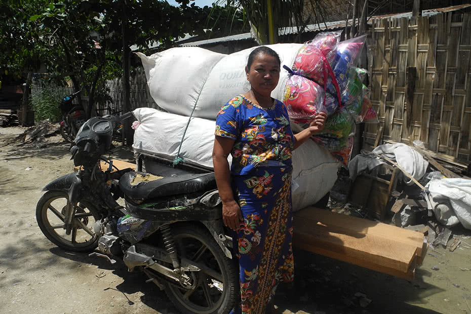 A woman standing next to a vehicle loaded with fabric scraps in Myanmar.