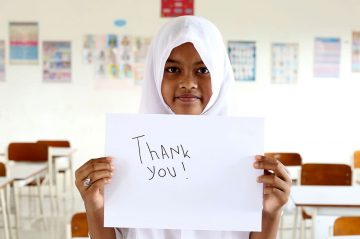 An Indonesian girl holds up a "Thank you" sign 10 years after her family were assisted by CARE during the 2004 Boxing Day tsunami.