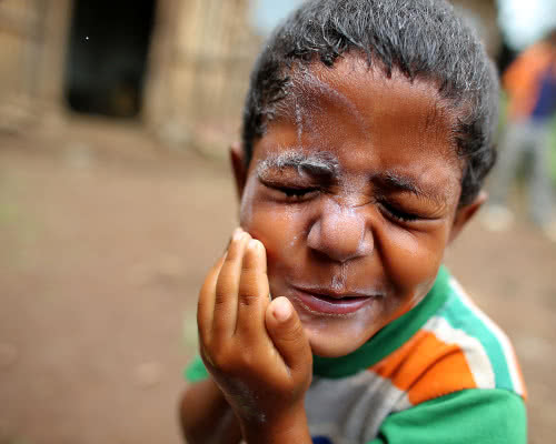 A boy washes his face with soap.