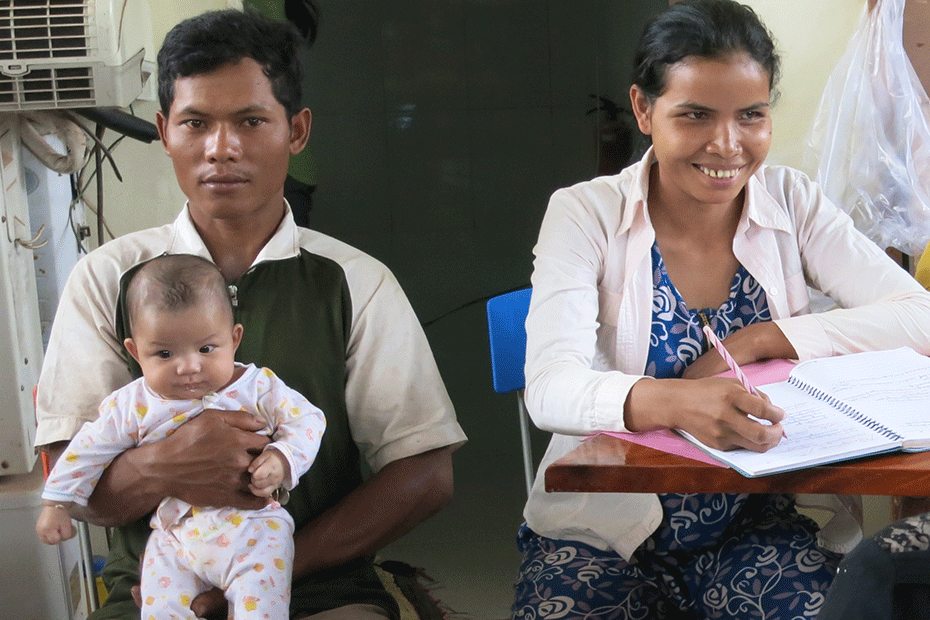A mother studies while her husband holds their baby.