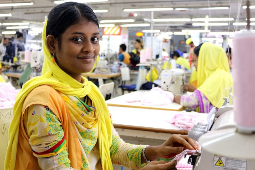 A female garment worker sitting at a sewing machine in Bangladesh