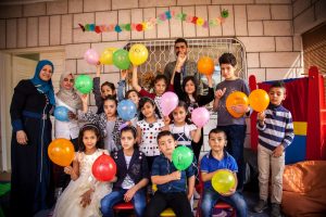 Children at a Safe Spaces play center, holding up balloons while learning about good hygiene practices