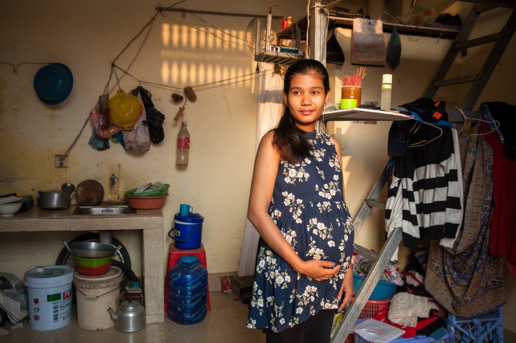 A young pregnant woman standing in her home