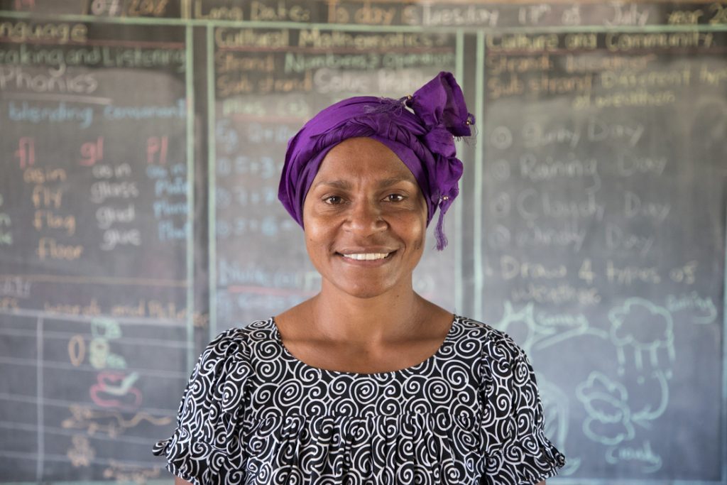 School teacher standing in front of blackboard in classroom