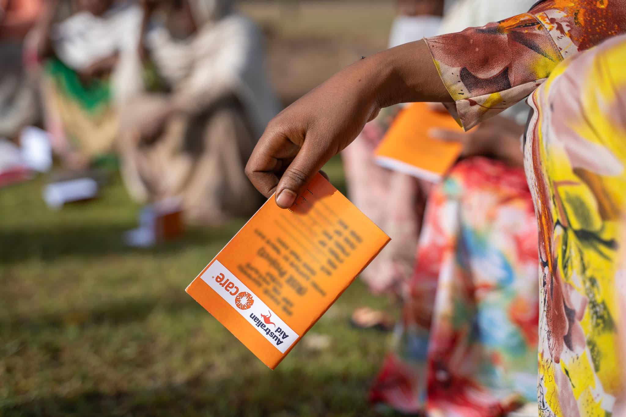 A member holds her RISE Project booklet during a community savings session in Amhara Region, Ethiopia.